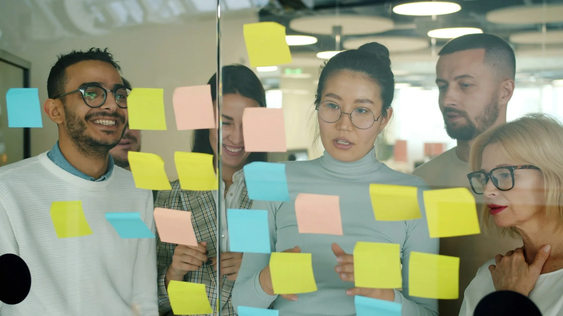 A team discussing priorities using sticky notes on a glass wall