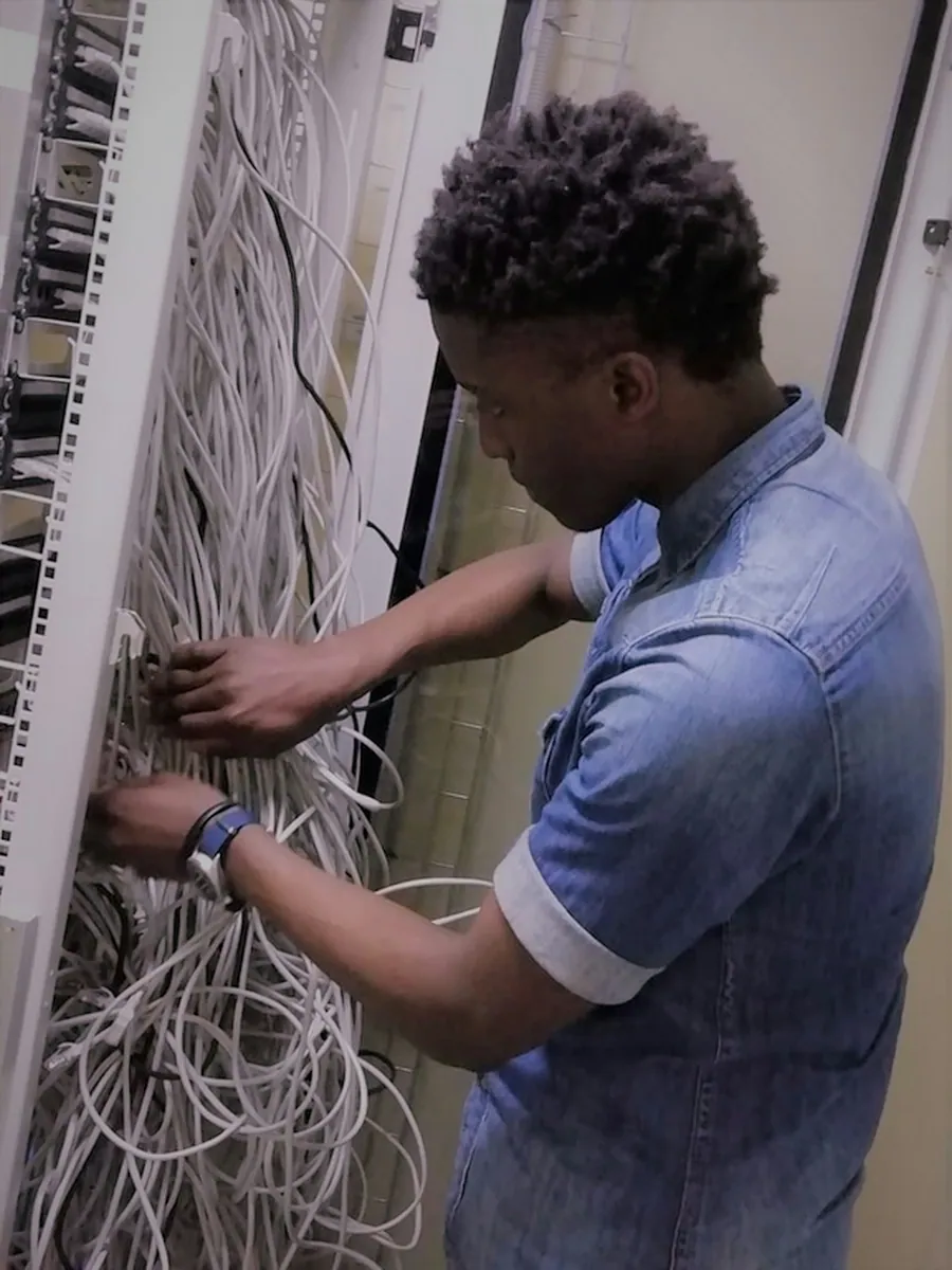 A technician assessing network cabling beside a rack